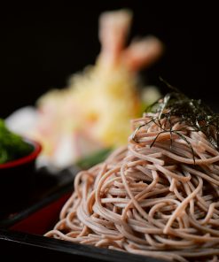 Appetizing soba noodles garnished with nori accompanied by tempura in a gourmet setting.