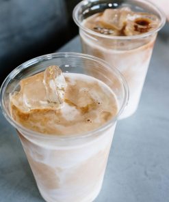 Two iced lattes in plastic cups with ice on a table, perfect for a refreshing break.
