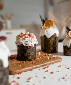 Decorative cupcakes topped with whipped cream and dried fruit on a wooden board, perfect for celebrating special occasions.
