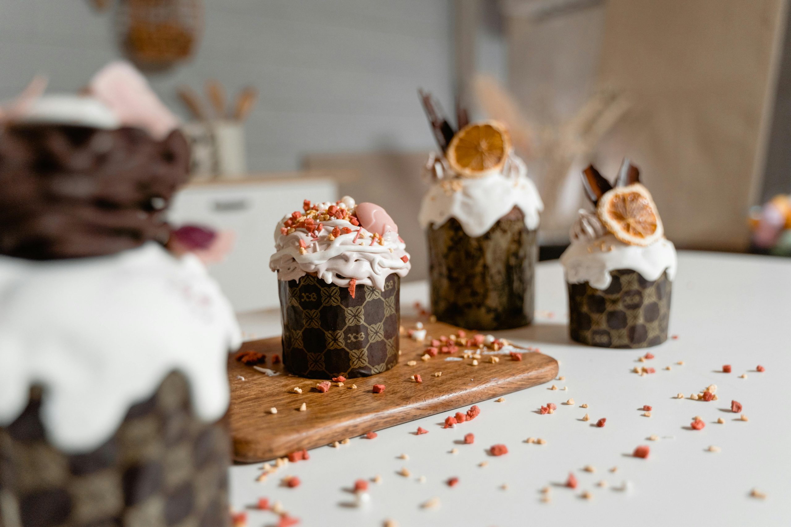 Decorative cupcakes topped with whipped cream and dried fruit on a wooden board, perfect for celebrating special occasions.